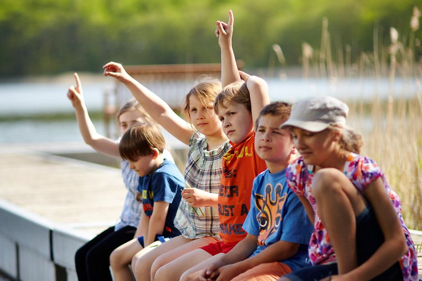 Kinder sitzen im Sommer auf einem Steg in Dambeck in Mecklenburg-Vorpommern