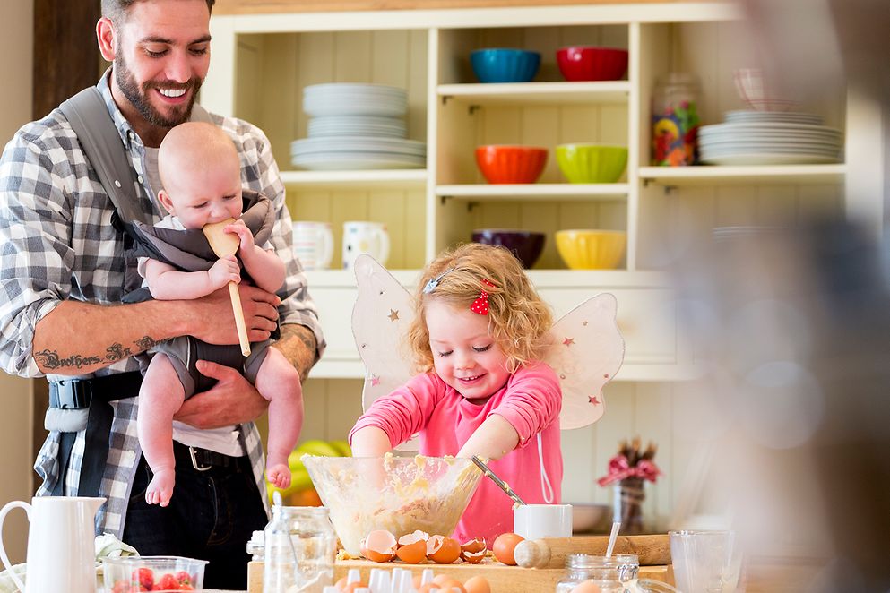 Ein Vater bereitet mit zwei Kindern in der Küche Essen zu.