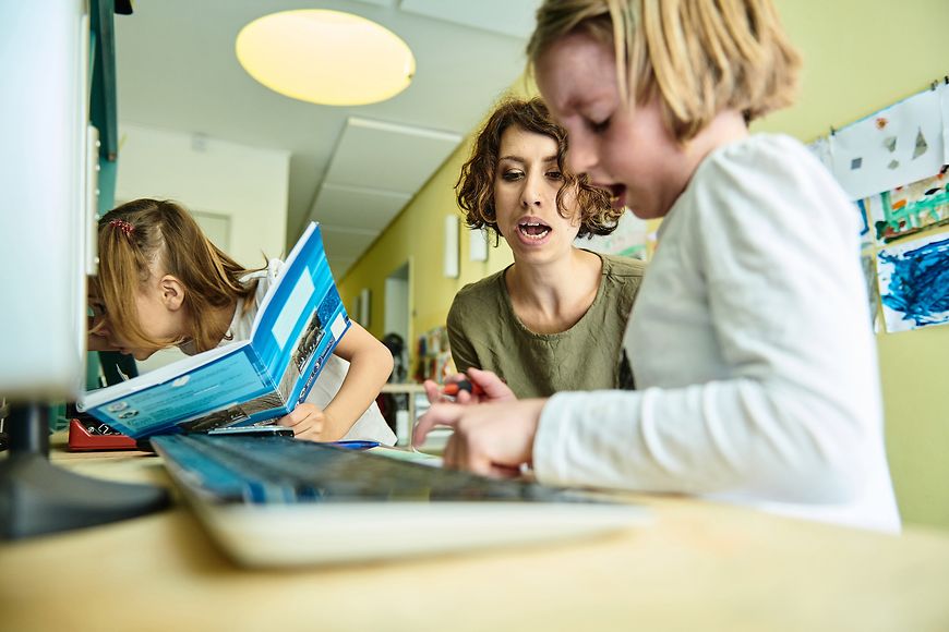 Eine Frau sitzt mit zwei Mädchen am Laptop