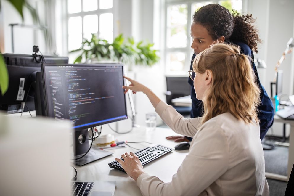 Zwei Geschäftsfrauen, die im Büro am Computer zusammenarbeiten