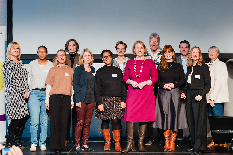 Ein Gruppenfoto mit Lisa Paus und weiteren Personen. Einige von ihnen halten Urkunden in der Hand.