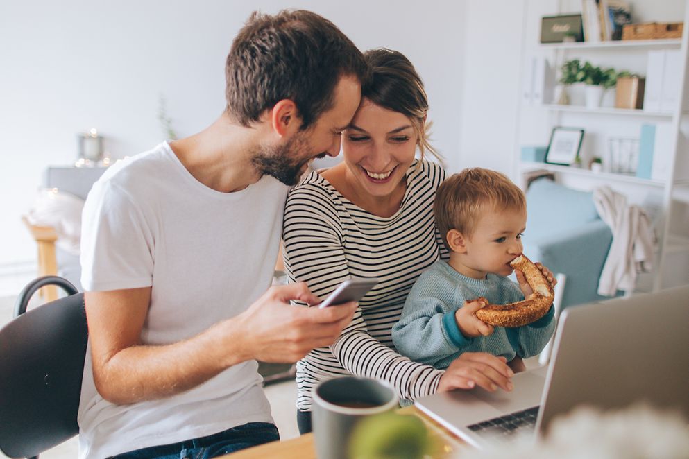 Junge Familie in einer Wohnung am Tisch mit einem Laptop