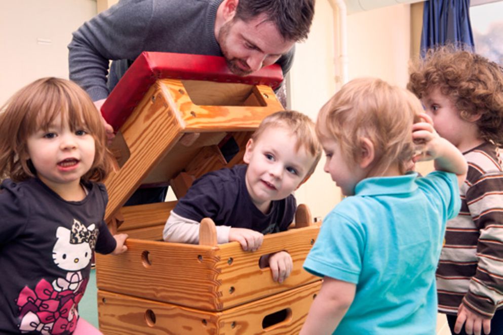 Kinder spielen mit einem Erzieher in der Kita