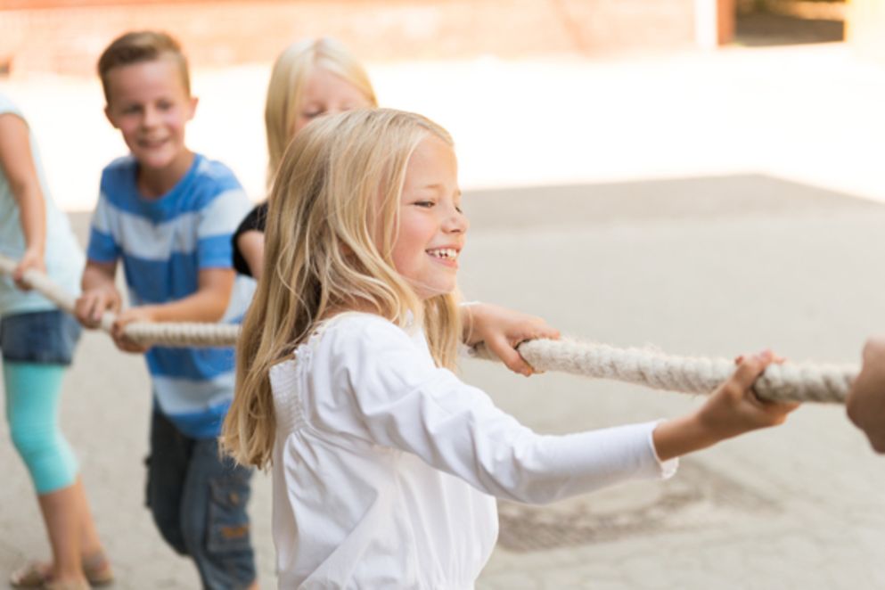 Lachende Kinder ziehen an einem Seil